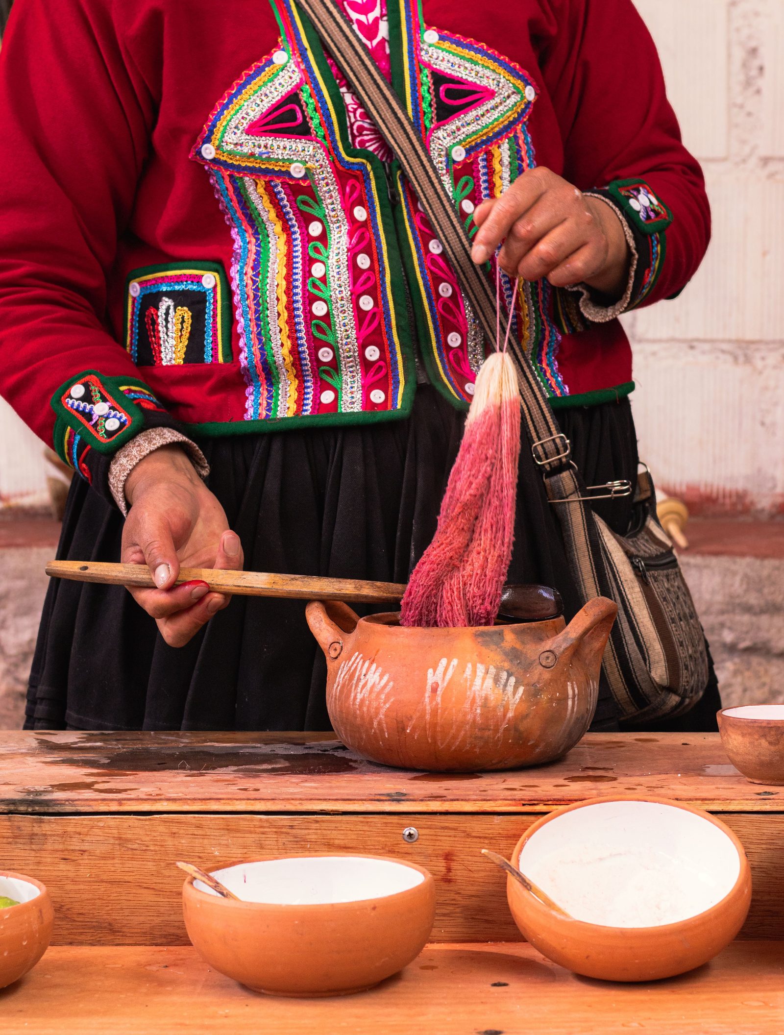 Hand-dyed wool yarn being lifted from a clay dye pot