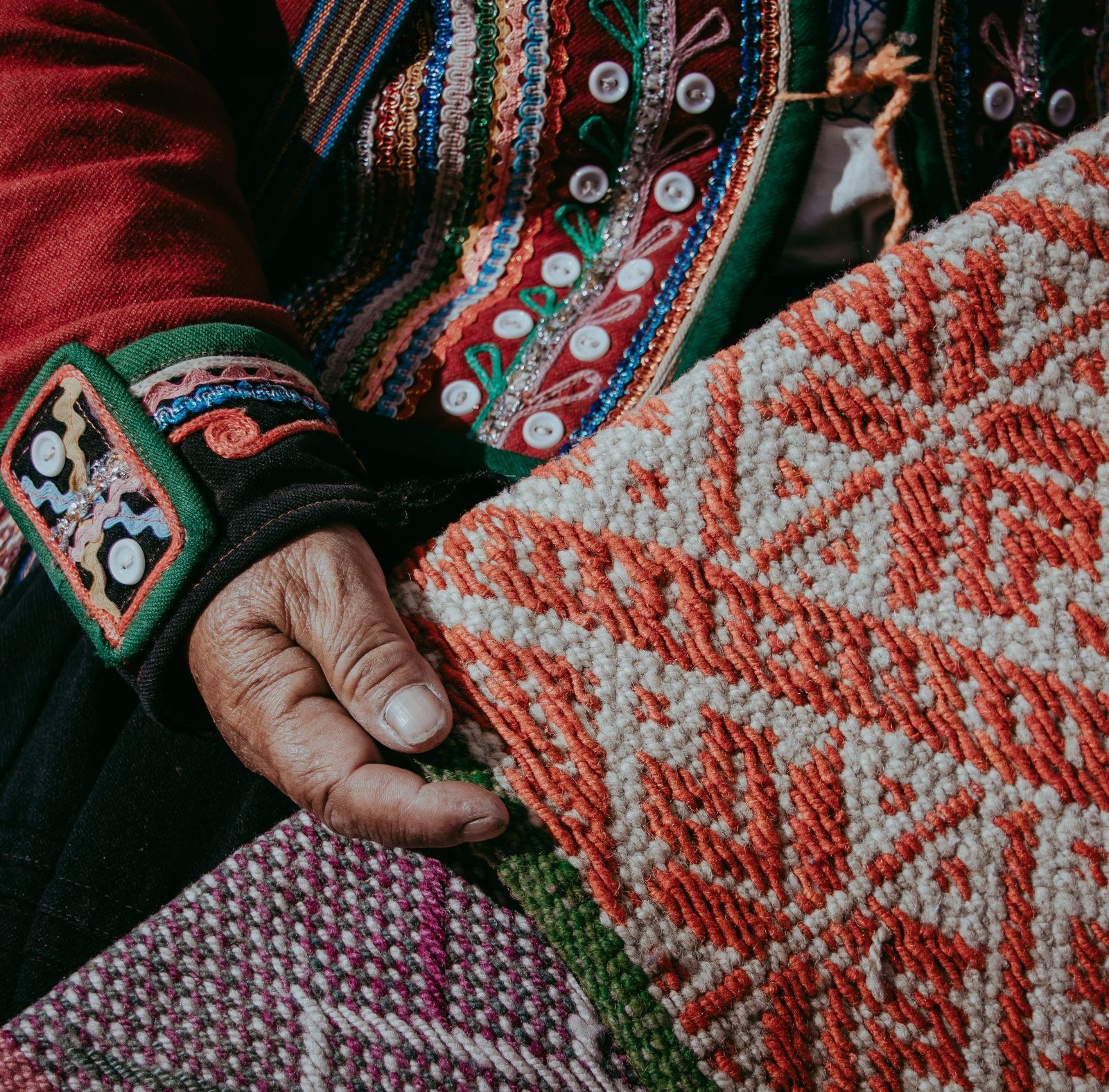 Close detail of a hand-woven textile pattern held in a weaver's hand